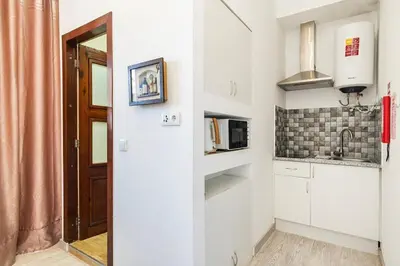 a small kitchen with white cabinets and a microwave at Cimo Apartments - Center Porto in Porto