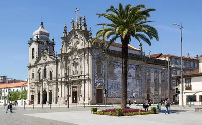 a large building with a palm tree in front of it at Studios Baixa Downtown Porto in Porto
