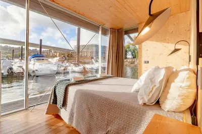 a bedroom with a bed and a large window at SLEEPBOAT- Modern Houseboat in Porto in Bicas