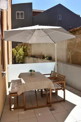 a table and chairs under an umbrella on a patio at O Refúgio das Caves by Horizon View Madeira in Vila Nova de Gaia