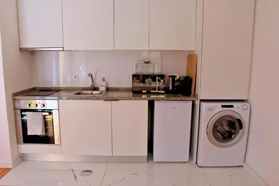 a kitchen with white cabinets and a washing machine at O Refúgio das Caves by Horizon View Madeira in Vila Nova de Gaia