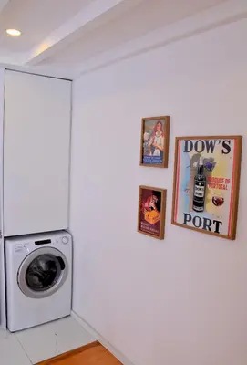 a laundry room with a washing machine and pictures on the wall at O Refúgio das Caves by Horizon View Madeira in Vila Nova de Gaia