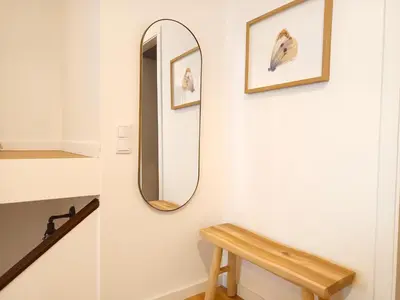 a hallway with a mirror and a wooden bench at Charming Campanhã Family Home in Porto