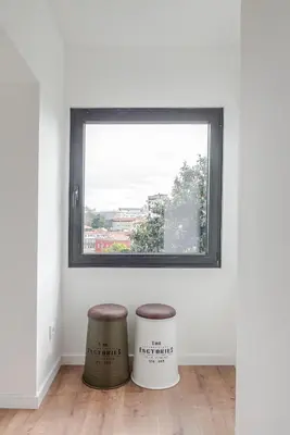 a window in a white room with two stools at DesKanzo Guest House - Raúl Doria in Porto