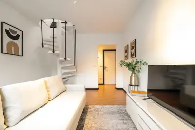 a living room with a white couch and a television at Duplex Studio in Art District by HostWise in Porto