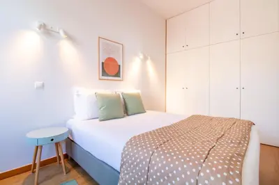 a small bedroom with a bed and a stool at Bright 1BR with Parking in Bolhão by LovelyStay in Porto