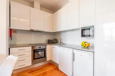 a kitchen with white cabinets and white appliances at Cozy Studio with Workspace by HostWise in Porto