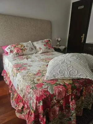a bed with a flowered blanket and pillows on it at Apartamento Quarto Compartilhado Porto in Porto