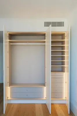 a closet with white shelves and a white wall at My Home is Yours in Porto