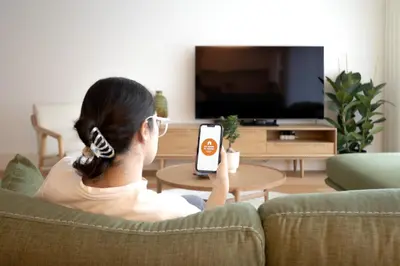a woman sitting on a couch holding a remote control at My Home is Yours in Porto