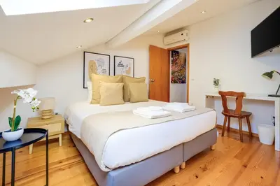 a bedroom with a large bed and a desk at Trindade Essence Duo Suites in Porto