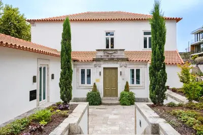 a white house with a green door and trees at City Retreat by Reframe stay in Porto in Porto
