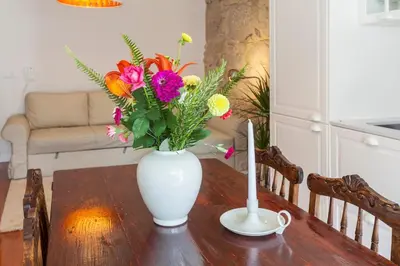 a white vase with flowers on a wooden table at Stunning Designer Flat with Balcony Heart of Porto in Porto
