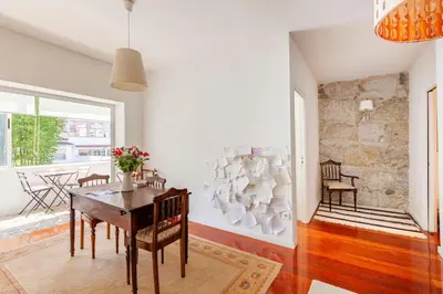 a dining room with a table and a stone wall at Stunning Designer Flat with Balcony Heart of Porto in Porto