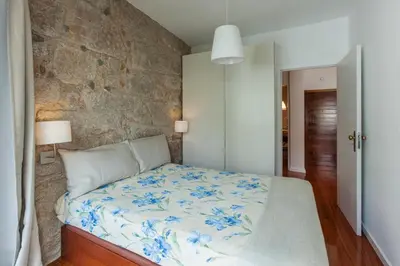 a bedroom with a bed with a stone wall at Stunning Designer Flat with Balcony Heart of Porto in Porto