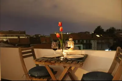 a table with two glasses of wine and a vase of flowers at Sweet apartment in Porto in Porto