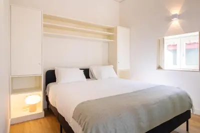 a bedroom with a large bed with white walls at Caldeireiros 95 by LovelyStay in Porto