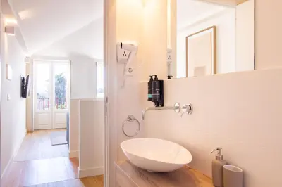 a bathroom with a white sink and a mirror at Caldeireiros 95 by LovelyStay in Porto