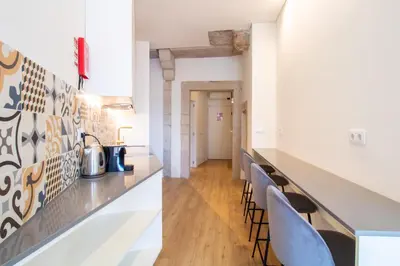 a kitchen and dining room with a counter and chairs at Caldeireiros 95 by LovelyStay in Porto