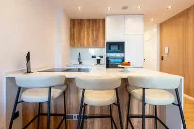 a kitchen with white cabinets and bar stools at Urban Terrace & Stylish Living Spaces by HostWise in Porto