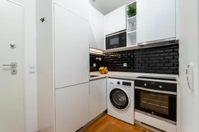a kitchen with white cabinets and a washer and dryer at Modern & Cozy Studio by HostWise in Porto
