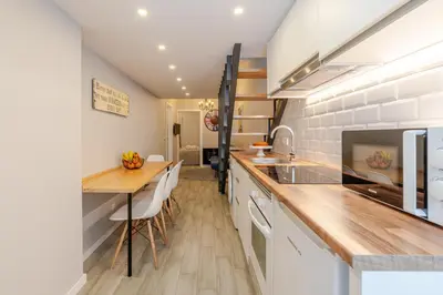 a kitchen with white cabinets and a wooden table at City Views Flats in Historic Porto by HostWise in Porto