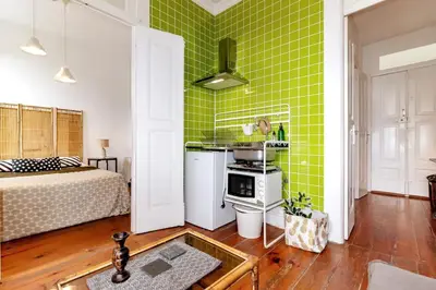 a room with a green wall with a bed and a kitchen at Ai Porto! Family 3 in Porto