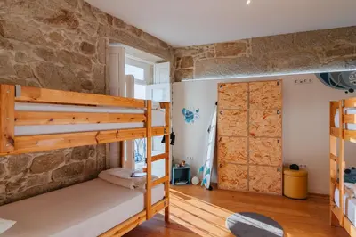 a room with two bunk beds and a stone wall at Happy Porto Hostel in Porto