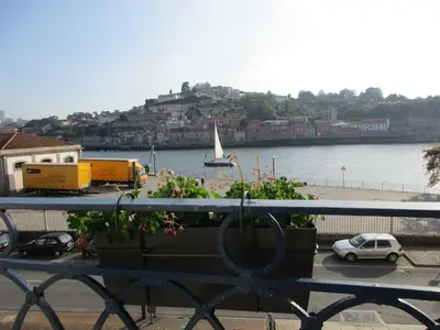 a balcony with a view of a river and a boat at Happy Porto Hostel in Porto