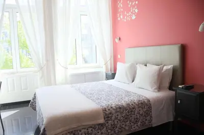 a bedroom with a white bed with red walls and windows at Pinho Apartments, Studios and Rooms in Porto