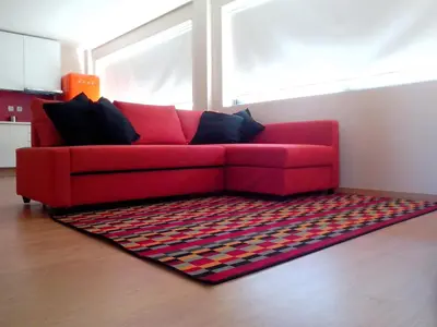 a red couch in a living room with a rug at Picaria Apartment in Porto