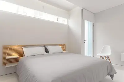 a white bedroom with a bed and a window at PortoWhite city lofts in Porto