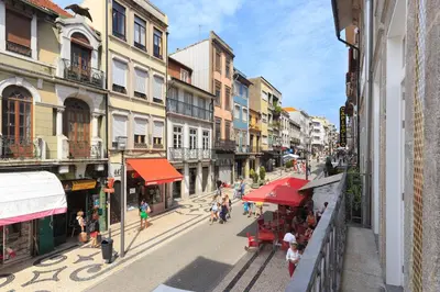 a city street with people walking and tables and buildings at PortoWhite city lofts in Porto