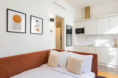 a bedroom with white walls and a brown couch with pillows at ApartmentsPorto - Alexandre Braga in Porto