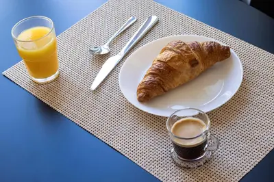 a plate with a croissant and a glass of orange juice at ApartmentsPorto - Alexandre Braga in Porto