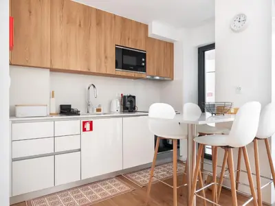 a kitchen with white cabinets and a table with white chairs at Gaia Bella Guest House in Vila Nova de Gaia