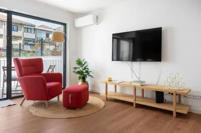 a living room with a red chair and a tv at Gaia Bella Guest House in Vila Nova de Gaia