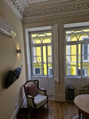 a living room with a chair and windows at Alma Porto in Porto