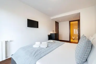 a white bedroom with a large bed with towels on it at Premium Flat w/ Pool, Gym & Garage by HostWise in Vila Nova de Gaia