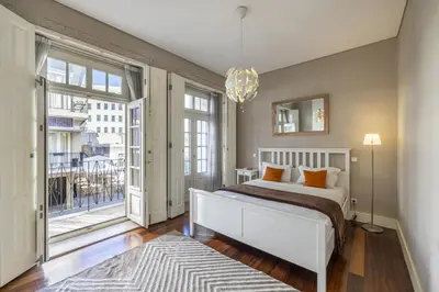 a bedroom with a white bed and a large window at Cardosas Square Living in Porto