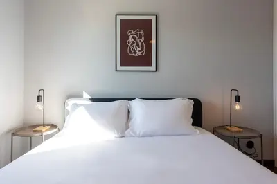 a bedroom with a white bed with two lamps at NEW! The Porto Wine Cellars Penthouse in Vila Nova de Gaia