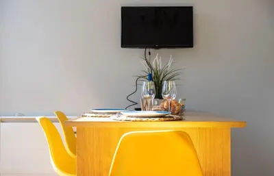 a dining room table with yellow chairs and a television at NEW! Blue Pearl Apartment in Porto
