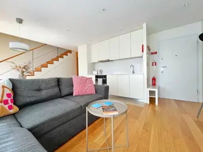 a living room with a gray couch and a table at Sunny rooftop duplex with elevator near iconic bridge in Vila Nova de Gaia