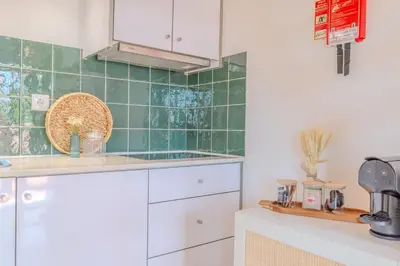 a kitchen with white cabinets and green tiles at VIVA Fontainhas Houses in Porto