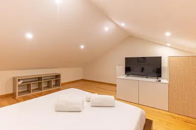 a bedroom with a large white bed and a flat screen tv at GuestReady - Porto stay with homely touches in Porto