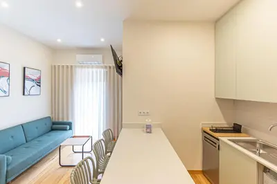 a living room with a blue couch and a kitchen at GuestReady - Porto stay with homely touches in Porto