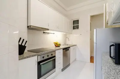 a kitchen with white cabinets and a refrigerator at Modern & Cozy Flat with Workspace by HostWise in Porto