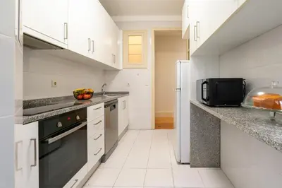 a kitchen with white cabinets and a black appliance at Modern & Cozy Flat with Workspace by HostWise in Porto