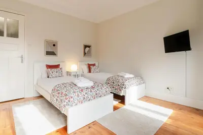 two beds in a white room with a tv at Modern & Cozy Flat with Workspace by HostWise in Porto