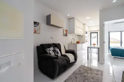 a living room with a black couch and a kitchen at Sleek Apartment with Balcony by HostWise in Porto